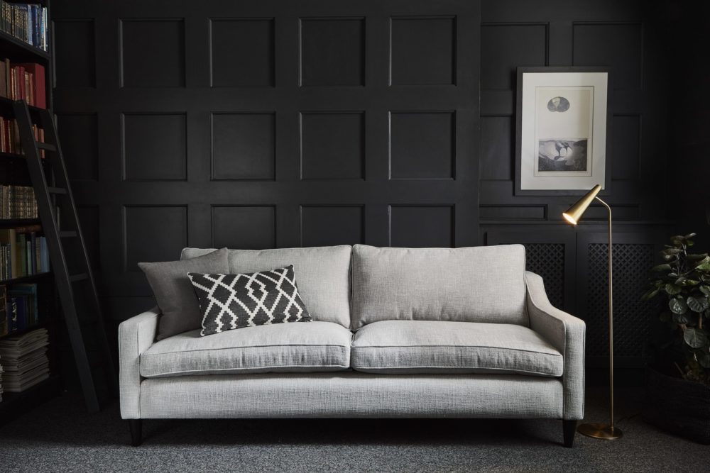 Mid-century modern interiors grey sofa with black feature wall and bookcase to show retro style living room